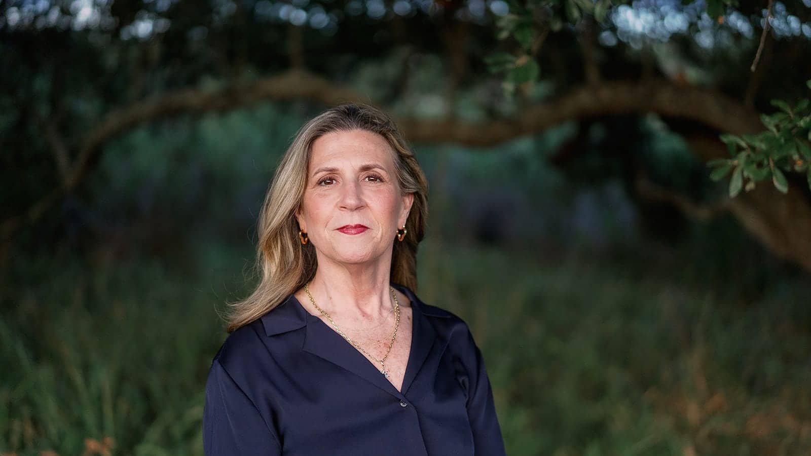 Michelle Dixon standing beneath the spreading branches of a live oak