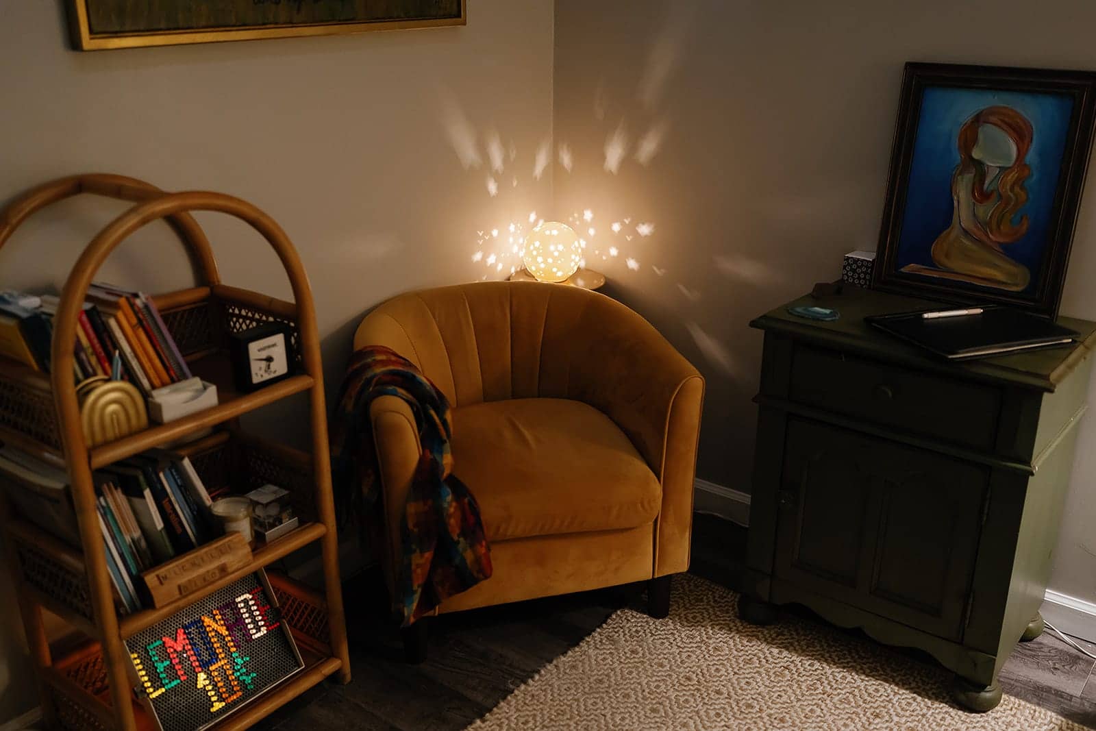 The counseling room at Pathways Mental Health, with a velvet armchair, a rattan bookshelf, framed artwork, and a lamp casting stars across the wall