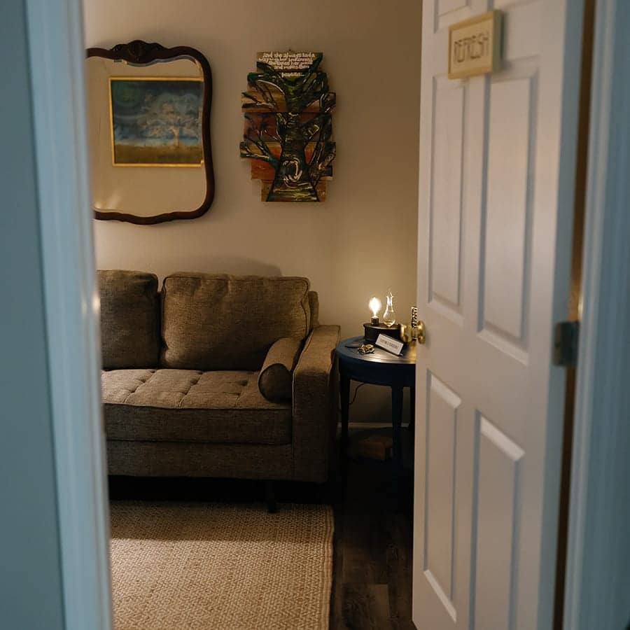 An open door looking into the counseling room, with a couch, a lamp, and a rug