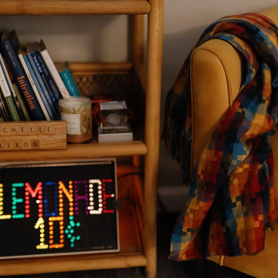 A bookshelf of counseling books beside a chair draped with a brightly coloured throw